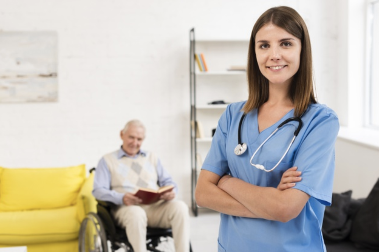 young nurse smiling and standing in front of a patient in the background. MEDIjobs