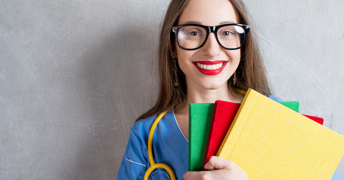 Portrait of a young nurse with colorful books and stethoscope on a wray wall background